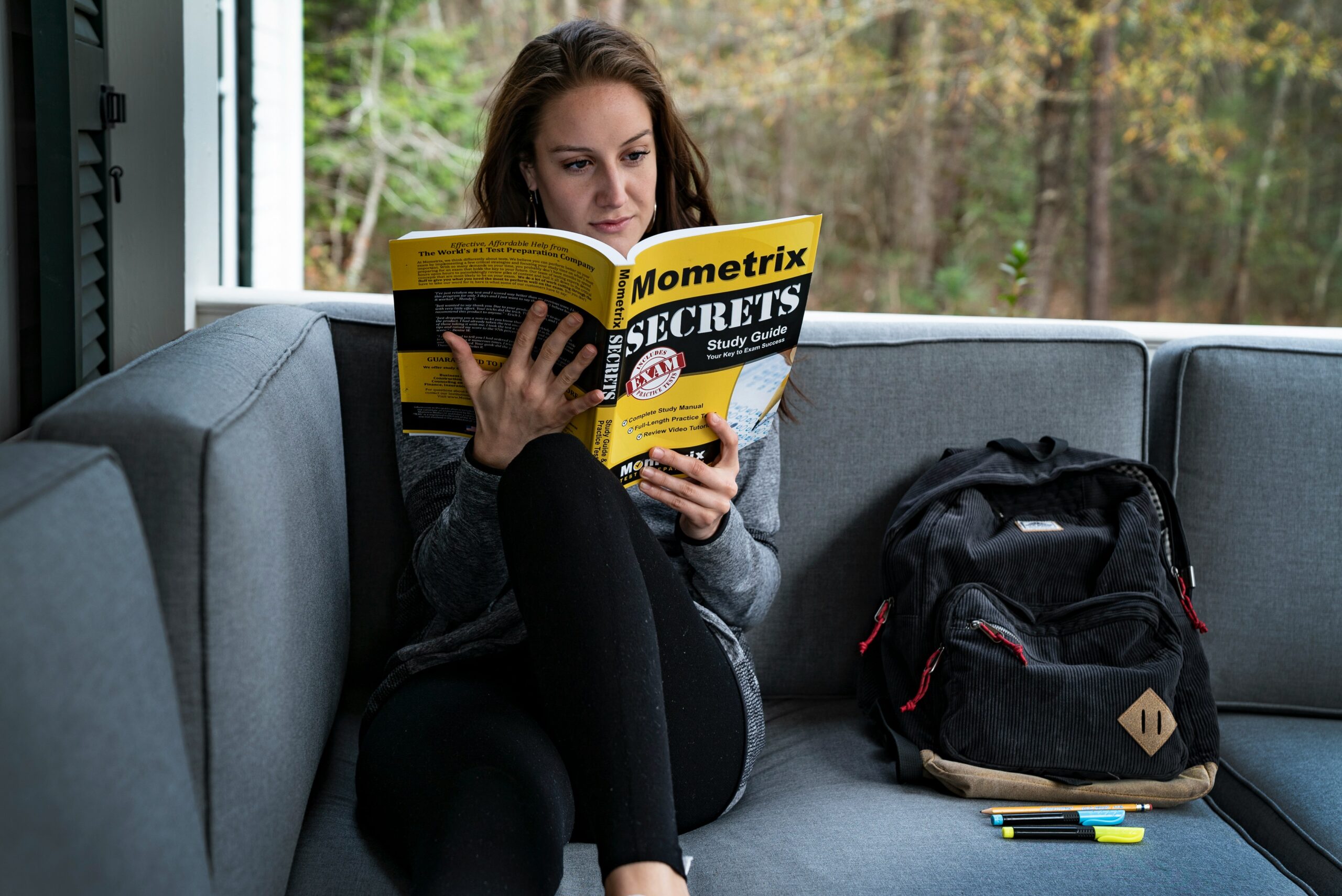 woman sitting on sofa beside bag while reading